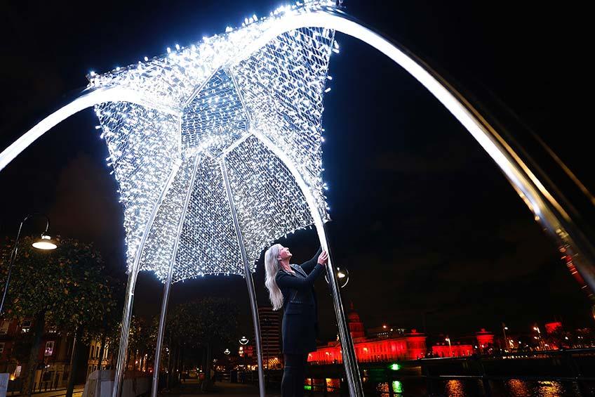 Photograph of the artist looking up at her sculpture at nighttime.