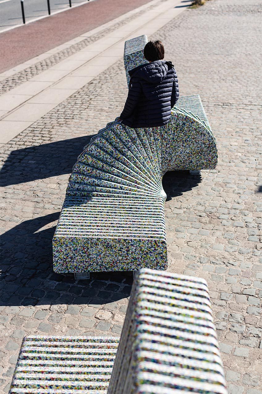 Person sitting with there back to us on colourful seat sculpture.