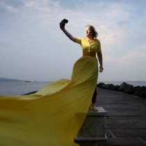 Woman in yellow dress standing on plinth with docklands in background
