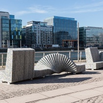 Two colourful seat sculptures in the sun looking onto the river Liffey