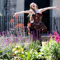 Opera perfomer dancing and singing in-between flowers