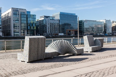Two colourful seat sculptures in the sun looking onto the river Liffey