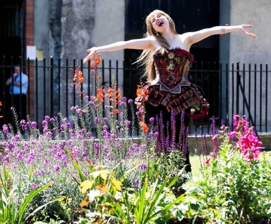 Opera perfomer dancing and singing in-between flowers
